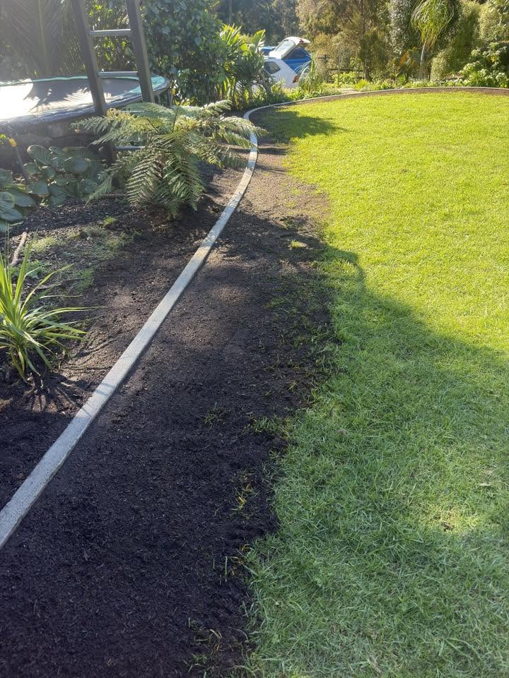 A hand-formed concrete mowing edge curving between a fresh mulched bed and a bright cut lawn